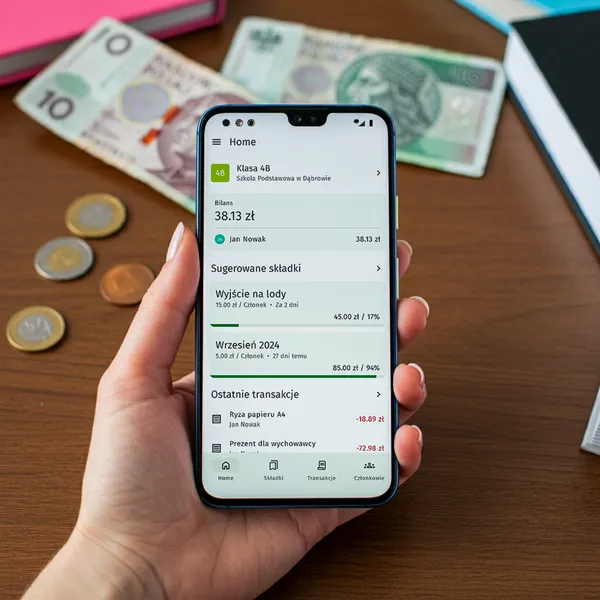 Ręka trzymająca smartfon z otwartą aplikacją Skarbnik.